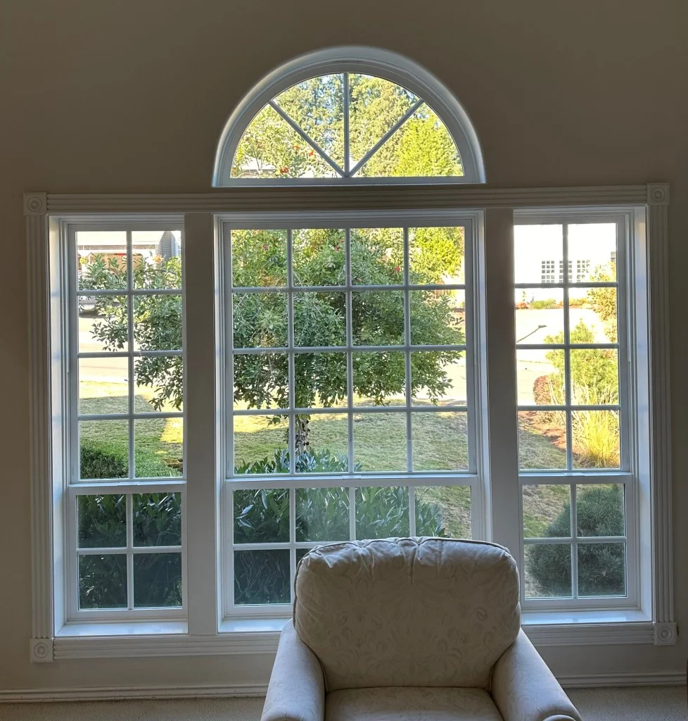 White grid-pattern double-hung windows with arched transom and white trim installed in a living room